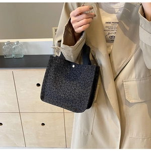 Détail du sac cabas en toile fleurie noire avec poignées robustes et bouton argenté