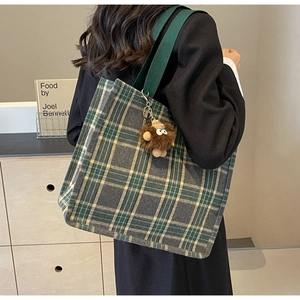 Dettaglio della borsa tote vintage a quadri con ciondolo di peluche e manici verdi