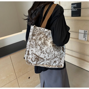 Detailed close-up of large canvas tote bag with brown floral patterns and wide strap