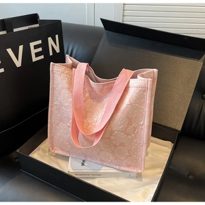 Détail du sac cabas rose avec motif floral en relief dans un coffret cadeau chic