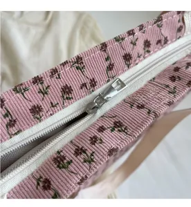 Détail de la fermeture éclair en métal sur un sac fourre-tout en velours côtelé rose