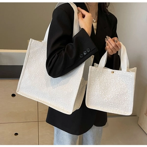 Détail de sacs cabas en toile blanche texturée avec jacquard et bouton doré chic