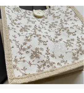 Dettaglio della borsa da pranzo in tela floreale con bottone decorativo e bordo in canapa
