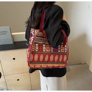 Detailed view of the ethnic woven pattern and red canvas strap on a large tote bag