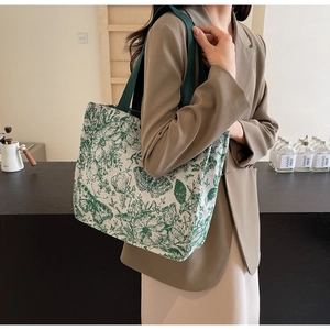 Detail of canvas tote bag with green floral pattern and butterfly print on a shoulder strap