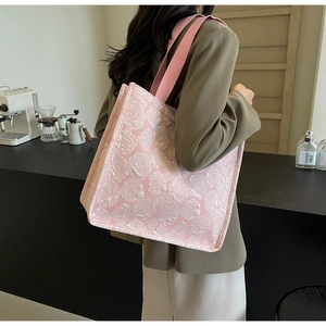 Détail de la texture jacquard rose rose sur un grand sac cabas porté par un modèle