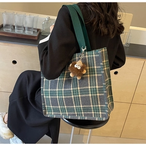 Dettaglio della borsa tote in tela a scacchi verde scuro con ciondolo in peluche marrone