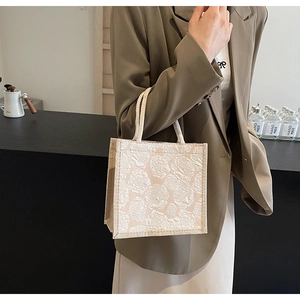 Detailed shot of beige floral jacquard linen tote bag with textured woven handles