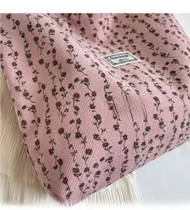 Détail du tissu en velours côtelé rose clair avec motif floral et étiquette de marque