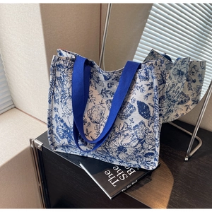Detail of blue floral Toile de Jouy canvas tote bag with woven shoulder straps