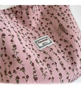 Gros plan du sac cabas en velours côtelé rose avec motif floral et étiquette de marque