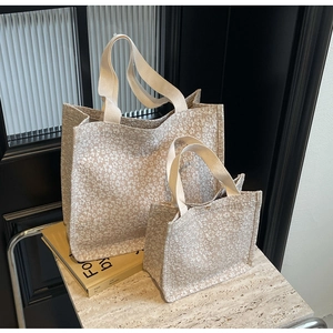 Détail d'un ensemble de sacs cabas crème avec gaufrage floral et poignées souples