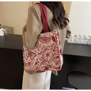 Detail of large canvas tote bag with red butterfly patterns and deep red shoulder straps