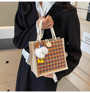 Close-up of linen tote bag with orange plaid pattern, cotton rope handle and plush charm