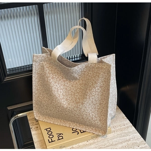 Gros plan du tissu gaufré à fleurs blanches et des poignées du grand sac fourre-tout