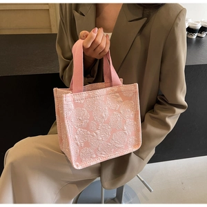 Gros plan d'un cabas rose avec texture de roses en relief et anses robustes