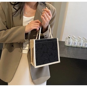 Detail of linen tote bag featuring black rose jacquard fabric and white woven rope handles