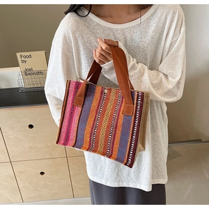 Detail of colorful woven ethnic tote bag with striped pattern and sturdy brown handles