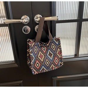 Detail view of woven ethnic geometric pattern tote bag hanging on a modern door handle