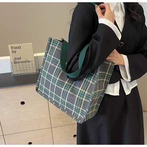 Dettaglio della grande borsa tote in tela a quadri con robusti manici verdi