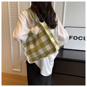 Détail du sac cabas en toile à damier vert avec un charmant pendentif cœur en peluche