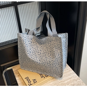 Détail d'un sac cabas bleu clair avec imprimés pâquerettes et anses tissées