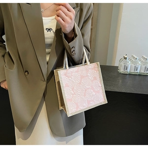 Detailed view of pink rose textured linen handbag held by model in minimalist setting