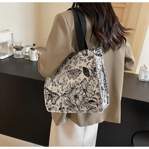 Detail view of butterfly floral canvas tote bag with black strap in a cafe setting