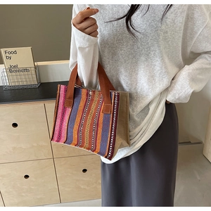 Detail of colorful striped bohemian tote bag with woven texture and brown handles