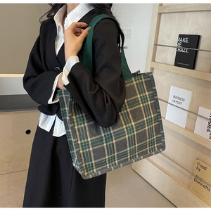 Dettaglio di una grande borsa tote in tela a quadri grigi con manici verdi in uso