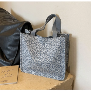 Sac fourre-tout à fleurs bleu-gris sur surface en pierre avec décor minimaliste