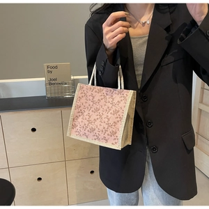 Dettaglio della borsa floreale con stampa rosa e manici in corda intrecciata