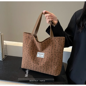 Détail du sac cabas en velours côtelé marron avec imprimé floral et étiquette tissée