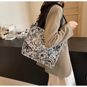 Detail of canvas tote bag showing vintage floral and butterfly prints with wide black straps