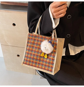 Detail of checkered linen bento bag with thick rope handles and plush monster charm