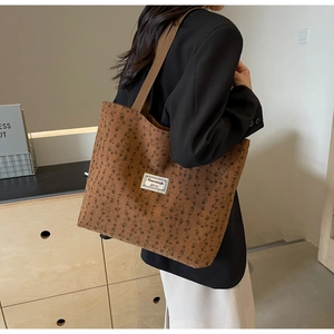 Détail du grand sac cabas en velours côtelé marron à fleurs porté à l'épaule