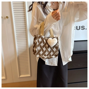 Detail of a brown knit tote bag with geometric patterns and a plush heart charm