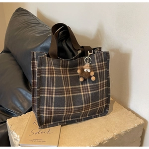 Dettaglio della borsa tote vintage a quadri con manici in tela e ciondolo in peluche
