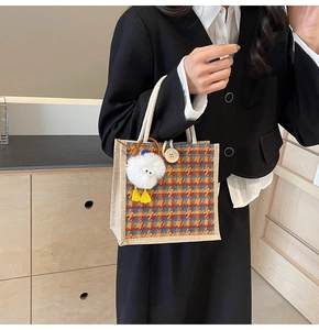 Close-up of linen tote bag with houndstooth pattern, wooden button and duck plush charm