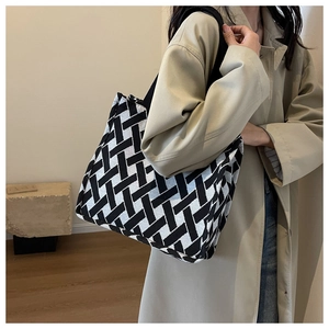 Detail of black and white woven tote bag showing geometric pattern and shoulder strap