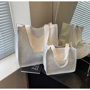 Vue détaillée du tissu jacquard floral blanc et des poignées en sangle des sacs cabas