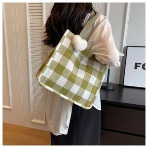 Détail du sac cabas à damier vert et blanc avec un charme de cœur en peluche blanc