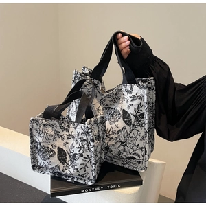 Detailed macro view of two canvas tote bags with black floral toile de jouy pattern
