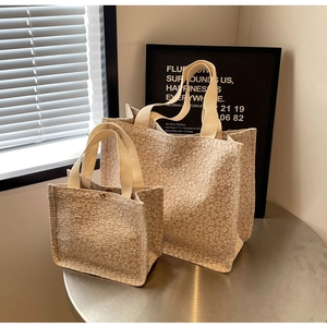 Détail de la texture jacquard floral 3D et des poignées tissées sur ce sac crème