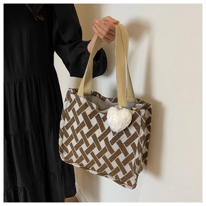 Detail of knit tote bag with brown geometric patterns and white plush heart charm