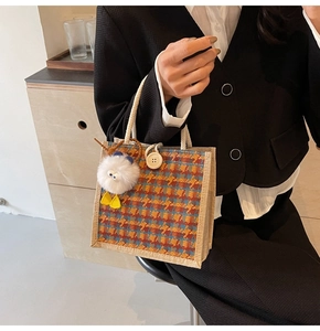 Close-up of retro plaid bento bag with white rope handle and cute plush chicken pendant