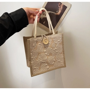 Detail of linen tote bag featuring embossed 3D rose pattern and round wooden button closure