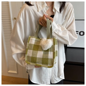 Gros plan du sac cabas à damier vert avec texture tissée et breloque cœur en peluche
