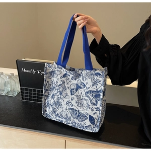 Close-up of vintage blue butterfly and floral print on a canvas tote with blue straps