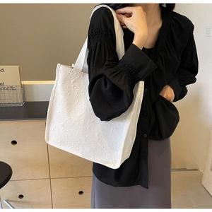 Détail de la texture jacquard rose et de la large bandoulière d'un grand sac blanc
